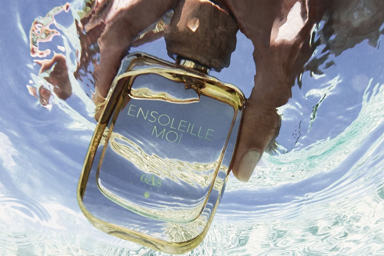 Beauty shot of hand holding Parfums Andre Gas Ensoleille moi Eau de Parfum bottle under water