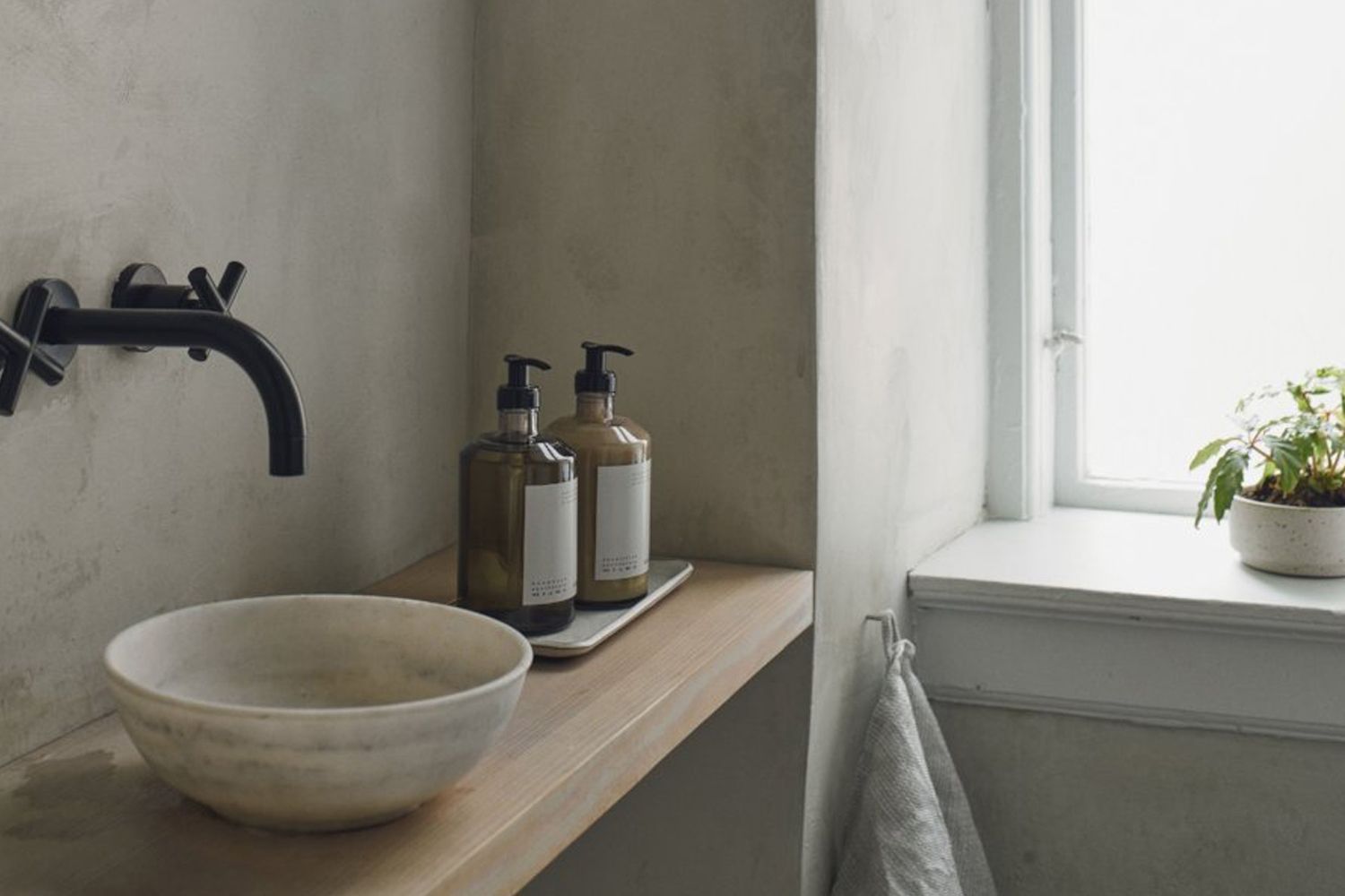 A Frama Apothecary Hand Wash and Hand Lotion next to a raised bathroom sink bowl