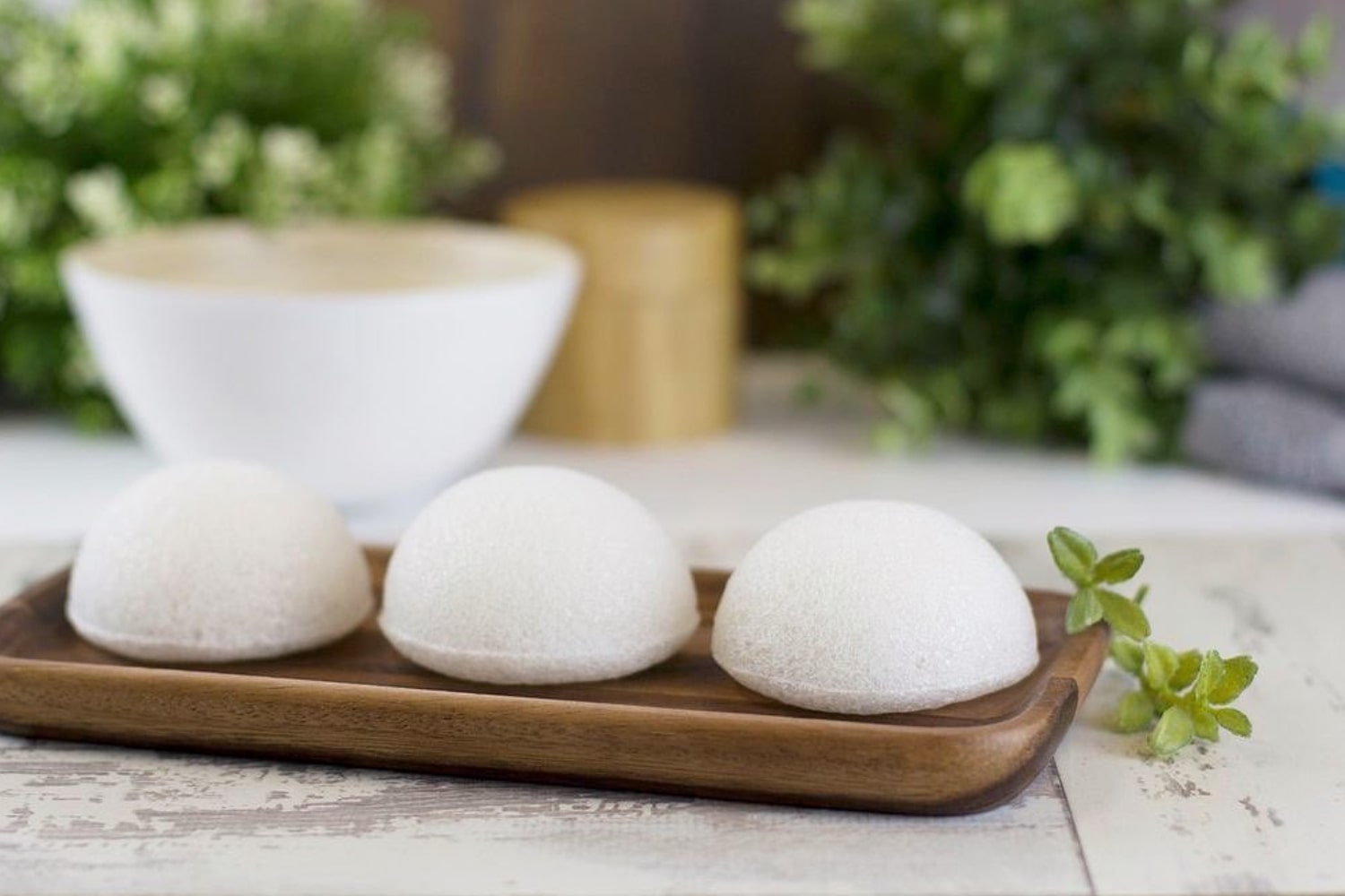 Three white Konjac Sponge Company facial sponges on a wood tray