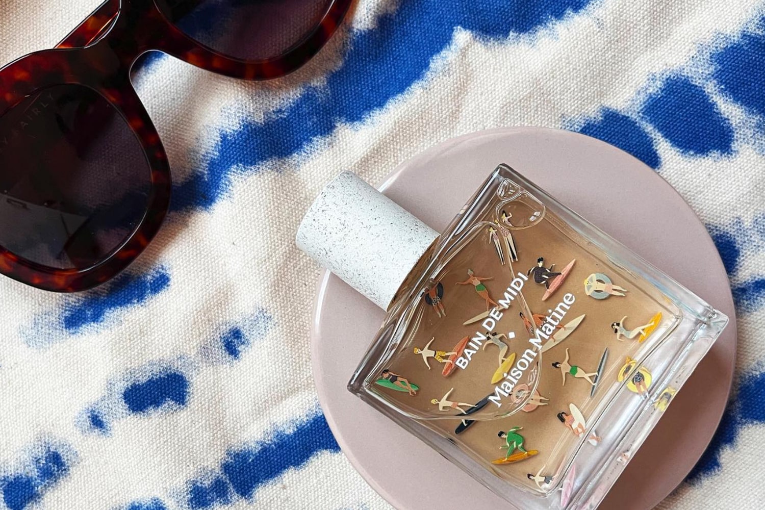 Maison Matine Bain de Midi Eau de Parfum on beach towel with sunglasses