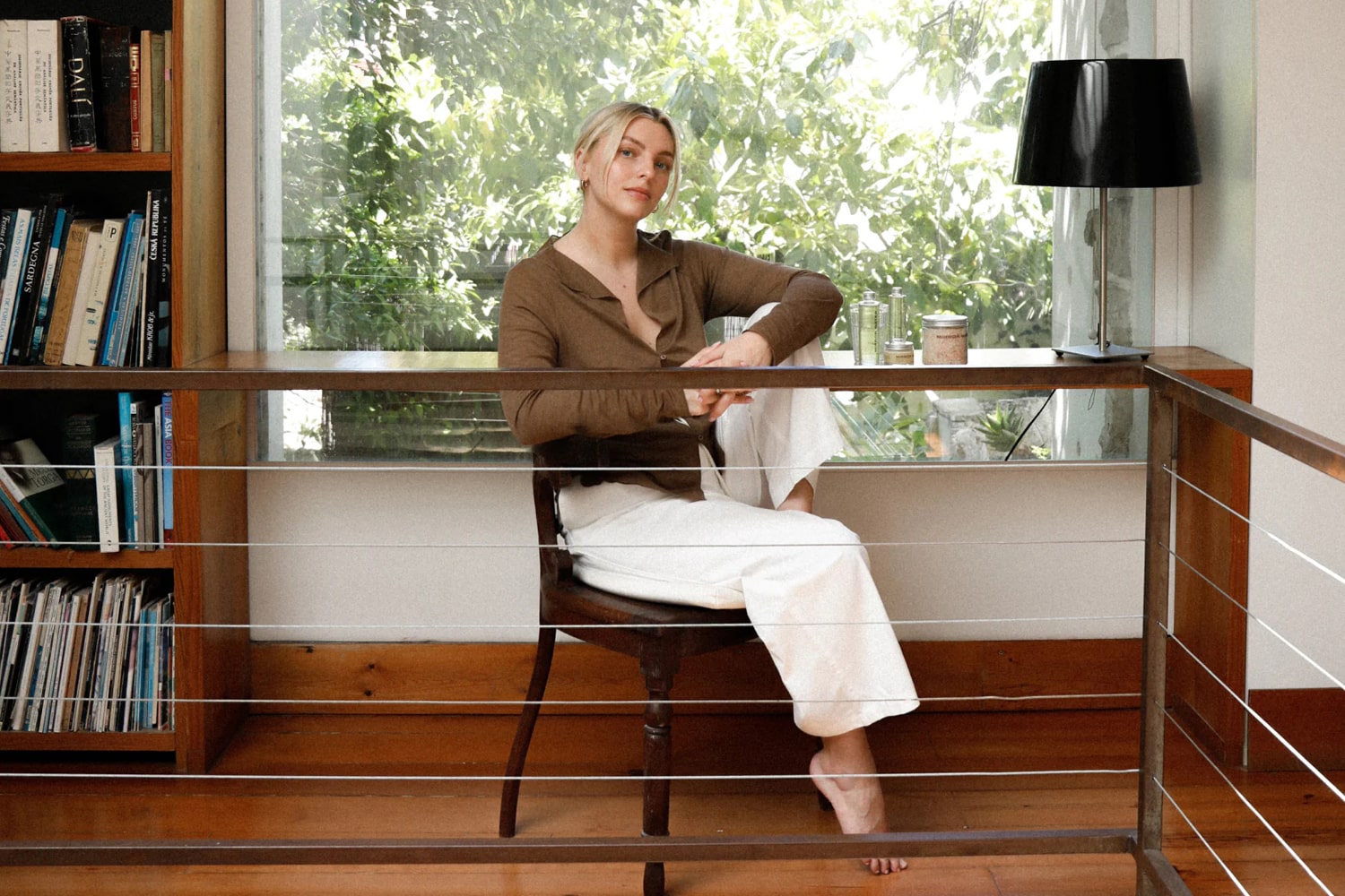Founder of Mirror Water Estee Lalonde sitting in chair in front of window with a few Mirror Water products on the desk behind her.