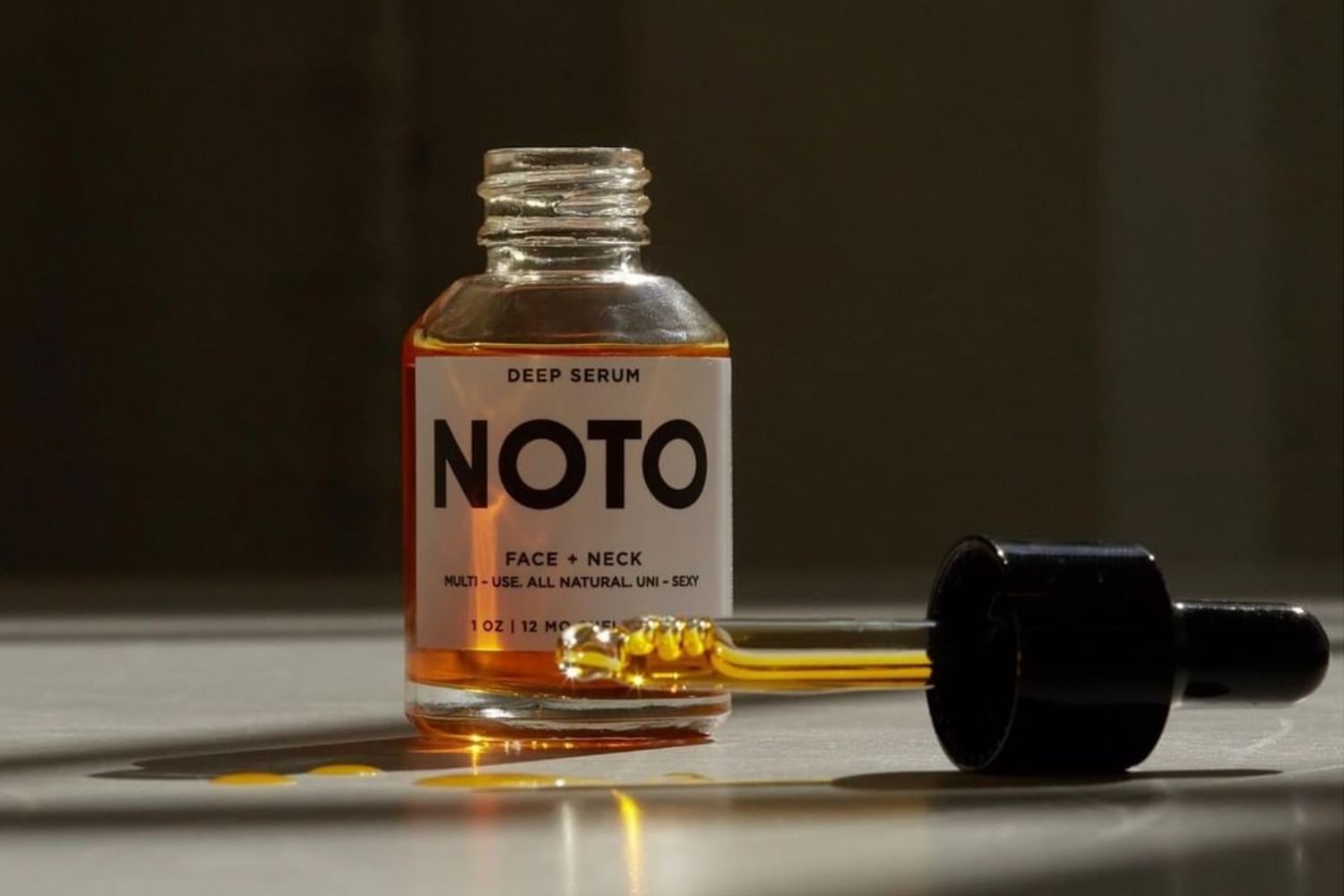 Dramatic shot of NOTO Botanics Deep Serum Mini with dropper top in front of bottle.