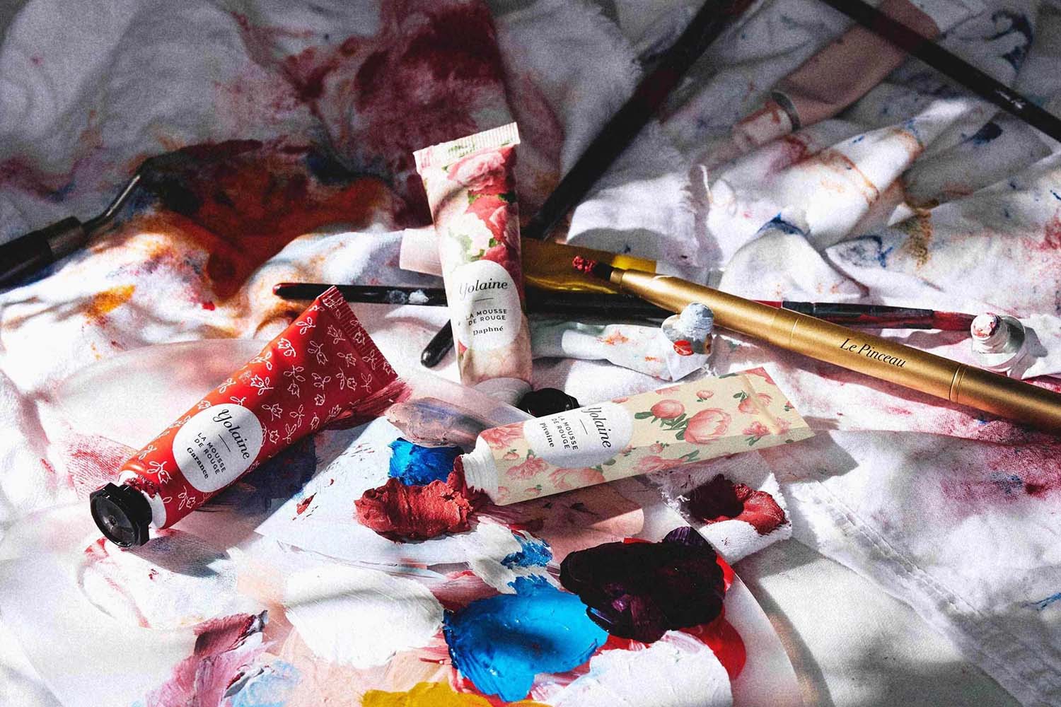 Lifestyle shot of an assortment of Yolaine La Mousse de Rouge for Cheeks & Lips colors and Retractable Lip Brush