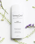 Lifestyle shot top view of Leonor Greyl Bain Vitalisant B Shampoo (200 ml) with purple and white flowers in the background
