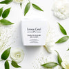 Lifestyle shot top view of Leonor Greyl Masque Fleurs de Jasmin Jasmine Conditioner (200 ml) with white flowers and green leaves in the background
