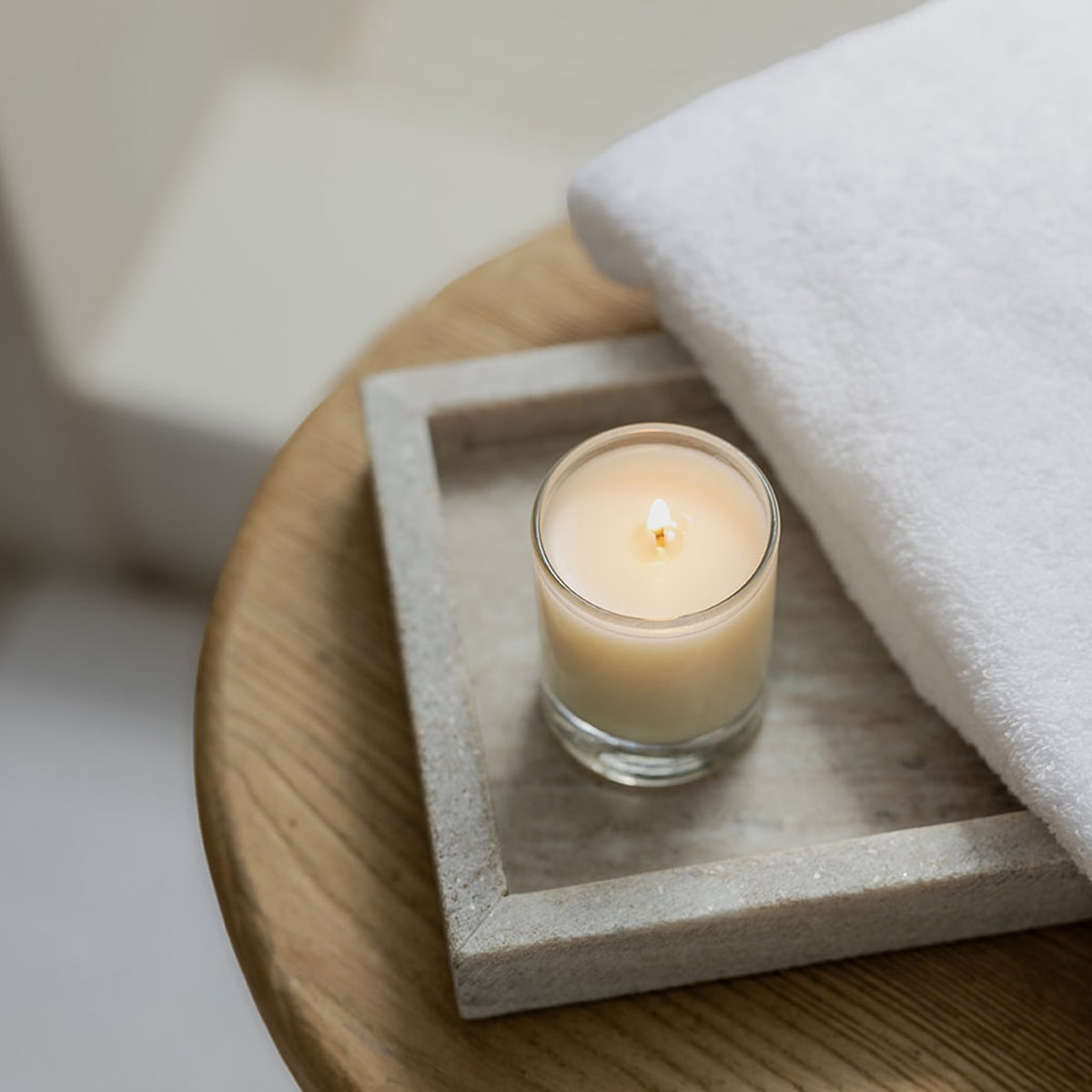 Kai Fragrance Nightlight Candle (3 oz) on a stone coaster with a white towel in the background