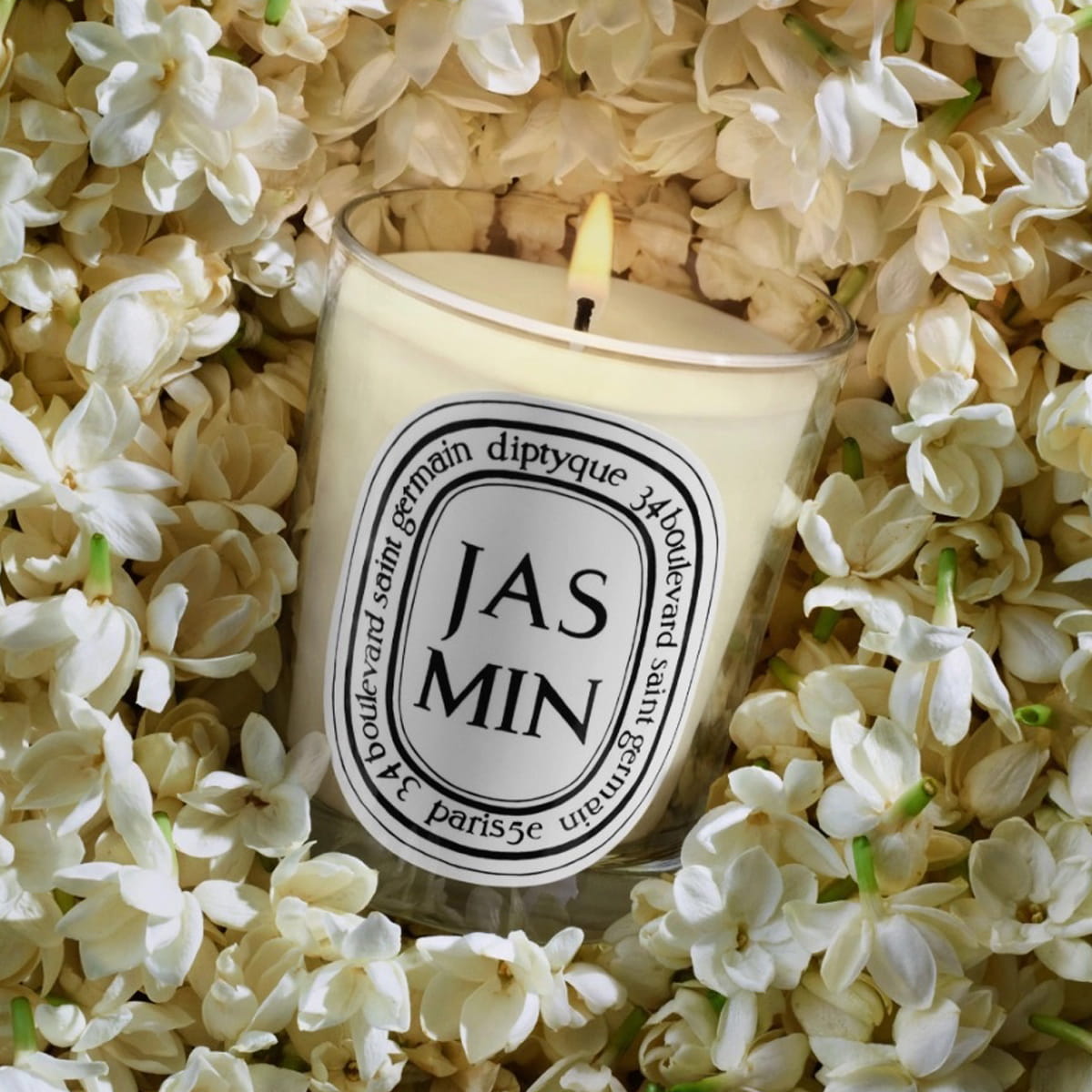Diptyque Jasmin Candle (190 g) - product shown on top of flowers. 