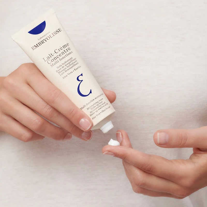 Embryolisse Lait Creme Concentre - model holding lotion tube and swatch on finger