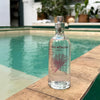 Lifestyle shot of Cinq Mondes Eau Egyptienne (100 ml) with pool in the background