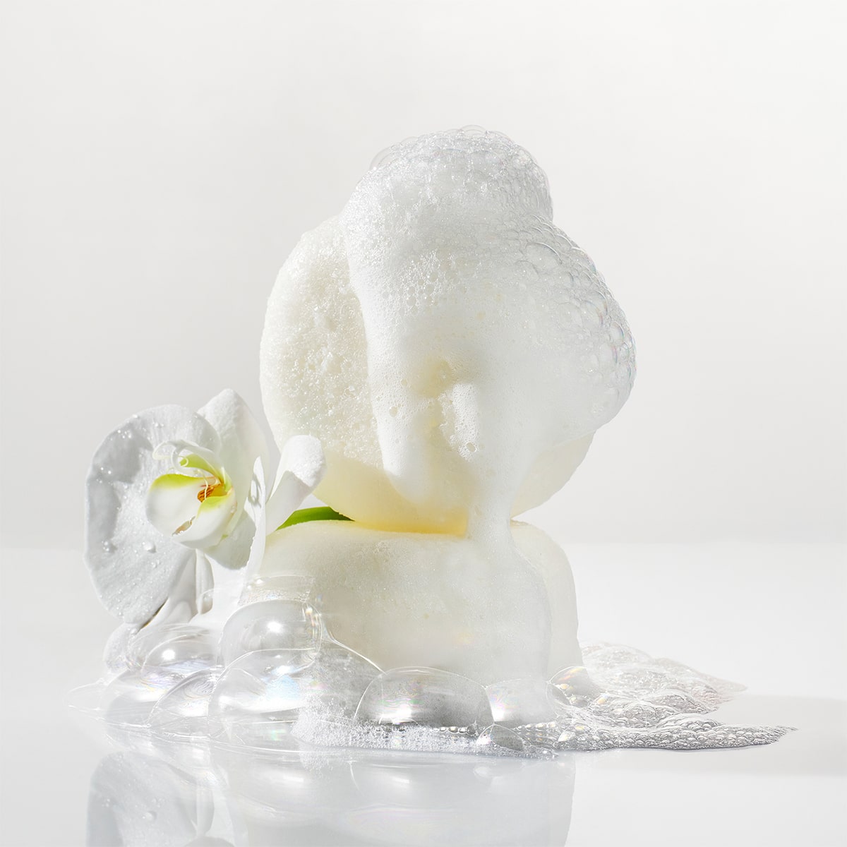 Kai Fragrance Body Buffer (2 x 2.75 oz.) shown with lather and next to a white flower
