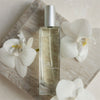 Kai Eau de Parfum Spray (1.7 oz/ 1 oz) with white flowers on a wooden surface
