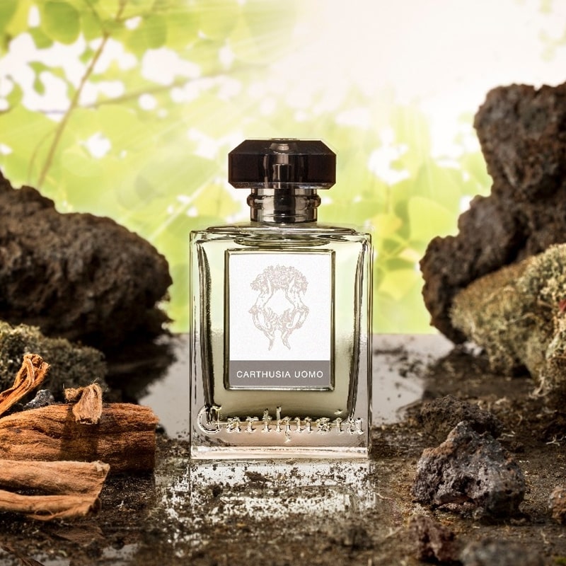 Lifestyle shot of Carthusia Uomo Eau de Parfum (100 ml) with rocks and forest in the background