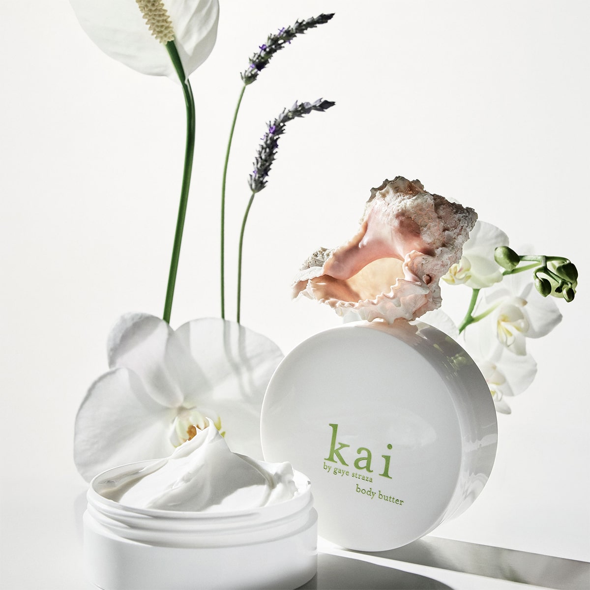 Kai Fragrance Body Butter (6.4 oz) with flowers on a light background