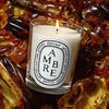 Diptyque Ambre (Amber) Candle (190 g) - product shown on top of amber. 