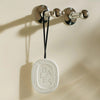 Lifestyle shot of Diptyque Scented Oval - Baies (1 pc) hanging from hook