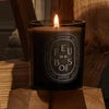 Diptyque Feu de Bois "Gris" Candle (300 g) -product shown on wood lit. 