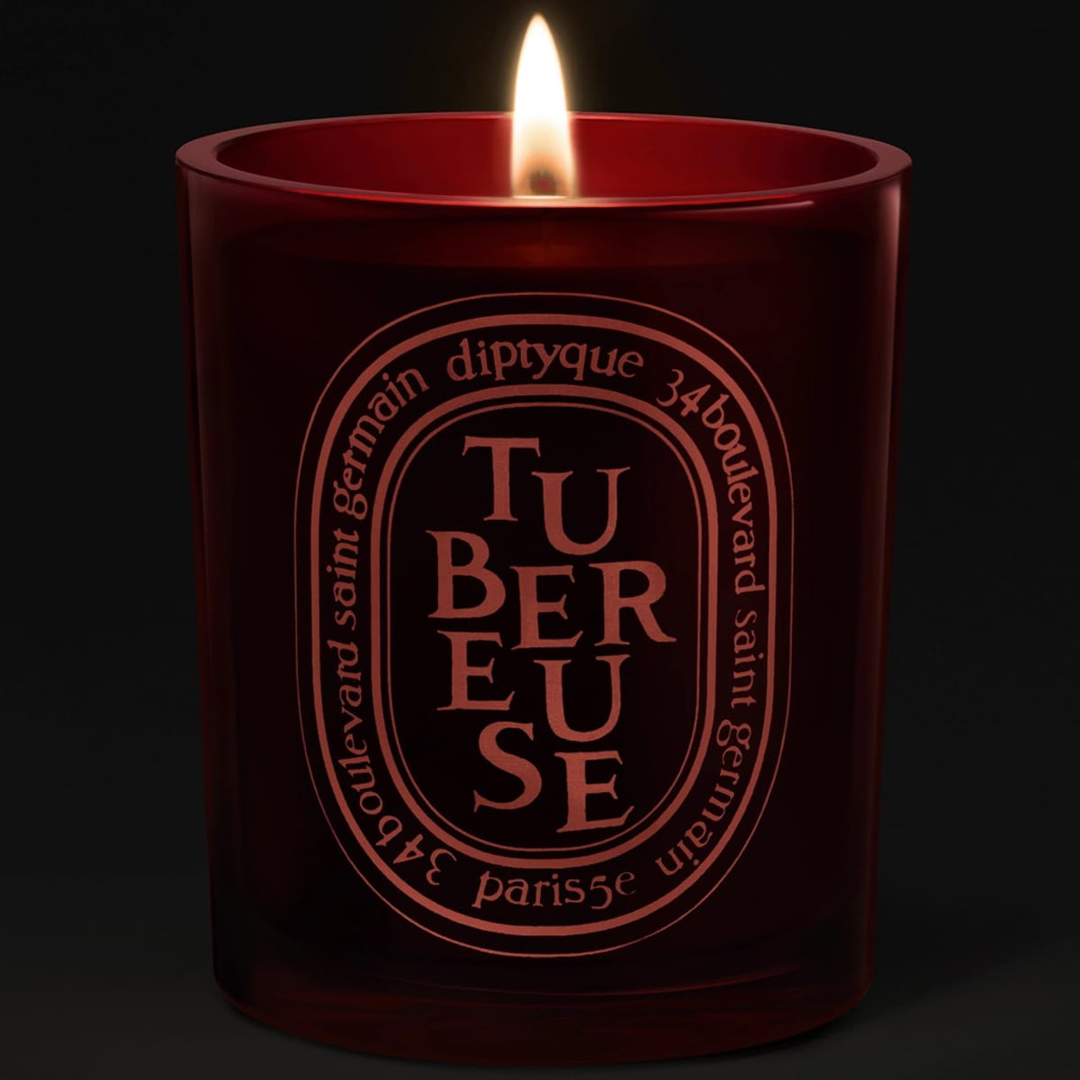 Diptyque Tubereuse Rouge Candle (300 g) - product shown on a dark background while lit. 