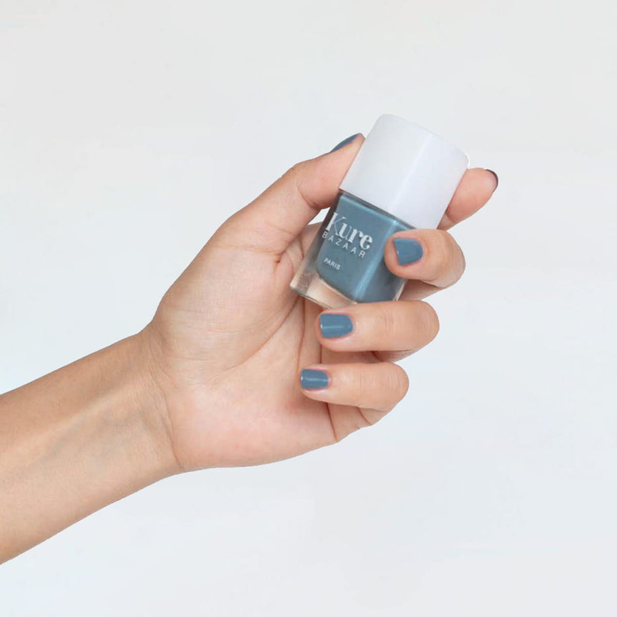 Model wearing and holding bottle of Kure Bazaar Nail Lacquer - Hipster (10 ml)