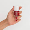 Close up of model wearing Kure Bazaar Nail Lacquer - Stiletto (10 ml) and holding bottle