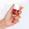 Close up of model wearing Kure Bazaar Nail Lacquer - Bohemian (10 ml) and holding bottle