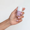 Close up of model wearing Kure Bazaar Nail Lacquer Fuji (10 ml) and holding bottle