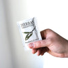 Close up of model holding single packette of Herban Essentials Eucalyptus Towelette
