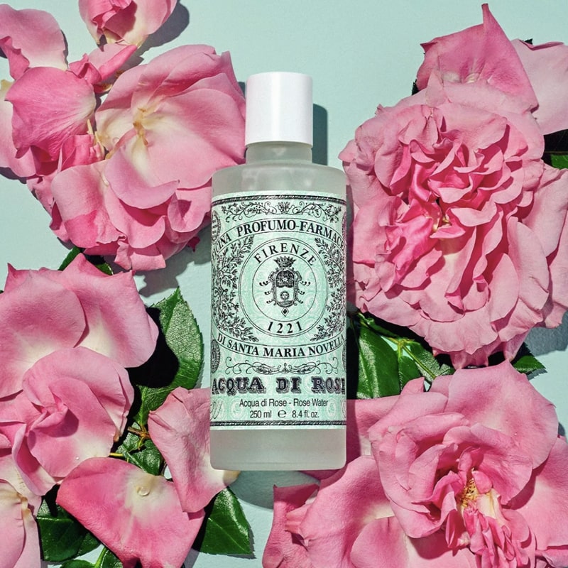 Lifestyle shot top view of Santa Maria Novella Rose Water (250 ml) with pink roses in the background
