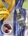 Lifestyle shot top view of Laboratory Perfumes Amber Eau de Toilette on blue and white stripe tablecloth