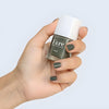 Close up of model wearing and holding bottle of Kure Bazaar Nail Lacquer - Khaki (10 ml)