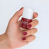 Close up of model wearing and holding a bottle of  Kure Bazaar Nail Lacquer - Tea Rose (10 ml)