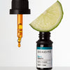 Lifestyle shot of Odacite Bu+L Buriti Lime Serum Concentrate (Firming) 0.17 oz with lemon wedge slice sitting on opened bottle