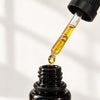 A close-up of de Mamiel Autumn Facial Oil dropper filled with facial oil