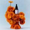 Lifestyle shot of Vintner's Daughter Active Botanical Serum (30 ml) sitting among orange flowers