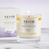 Lifestyle shot of NEOM Organics Tranquility Candle (185 g) burning with box in the background