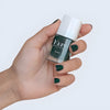 Close up of model wearing and holding bottle of Kure Bazaar Nail Lacquer - Kale (10 ml)