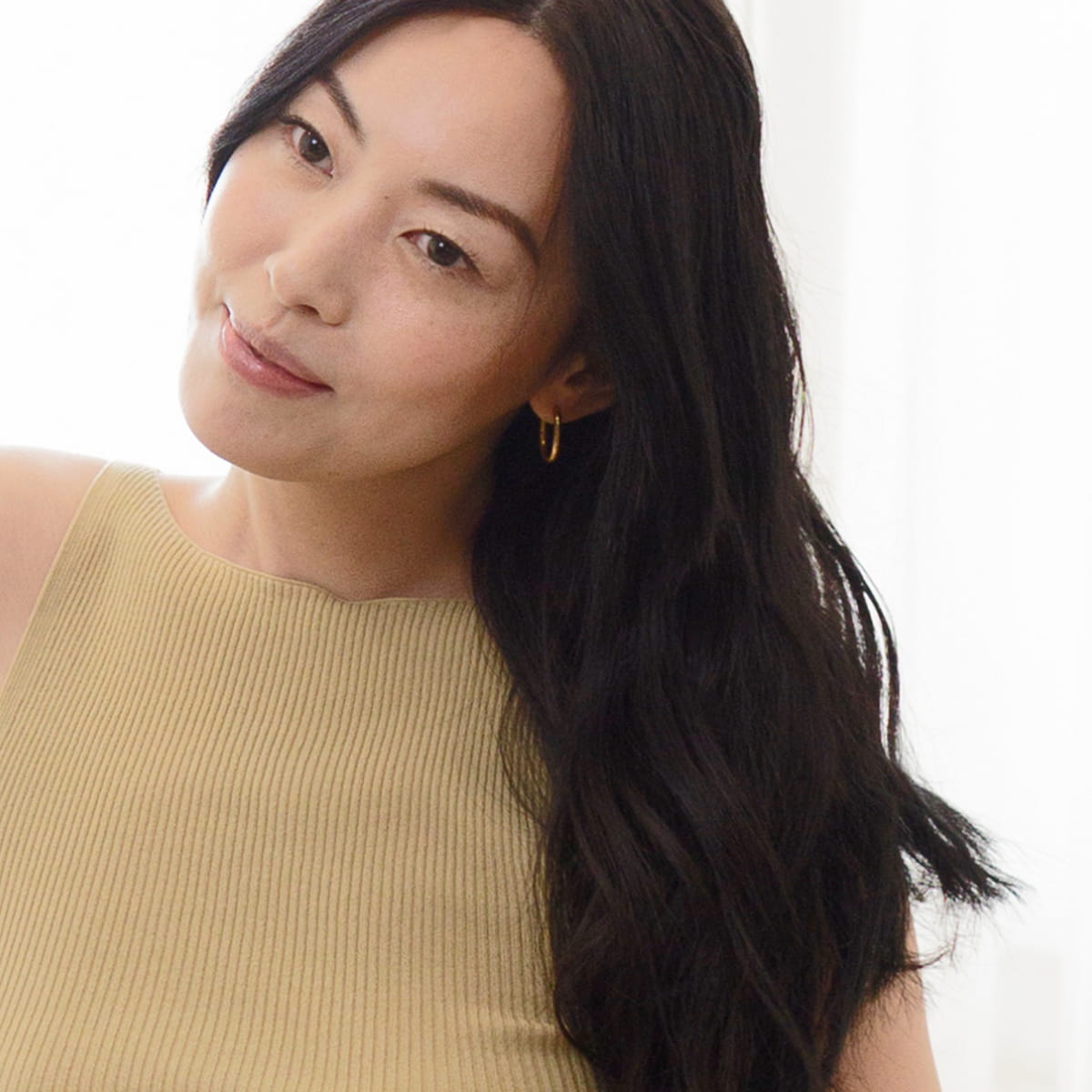 A woman with long dark hair shown after using Rahua Voluminous Dry Shampoo