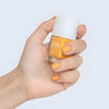 Close up of model wearing Kure Bazaar Nail Lacquer - Saffron (10 ml) and holding bottle