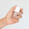 Close up of model wearing Kure Bazaar Nail Lacquer - Nude (10 ml) and holding bottle