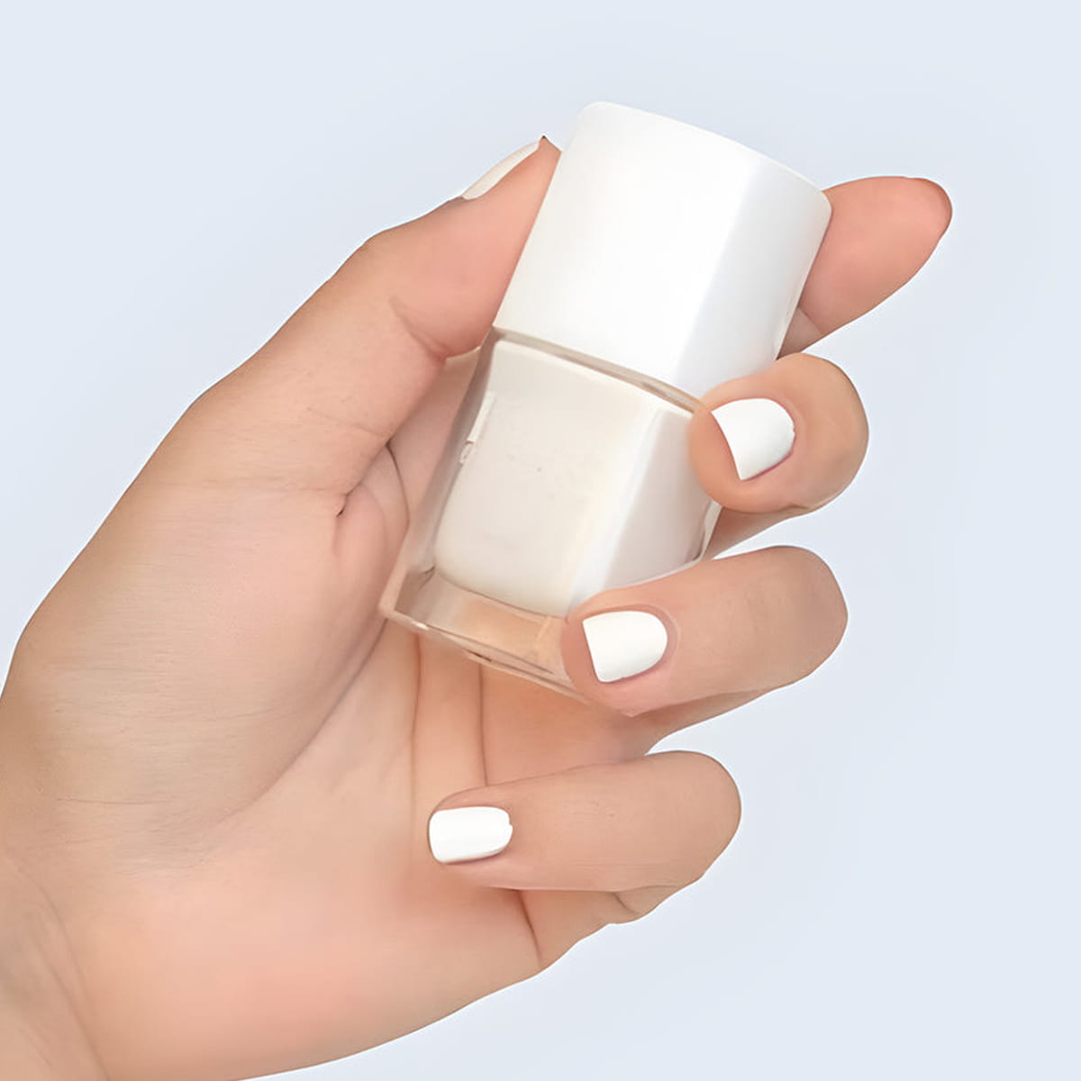 Close up of model wearing Kure Bazaar Nail Lacquer - French White and holding bottle (10 ml)