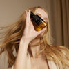 Model holding Oribe Gold Lust Nourishing Hair Oil (3.4 oz) with beautiful flowing hair