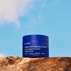 Ursa Major Golden Hour Recovery Cream (1.57 oz) - product shown on top of wood with blue sky