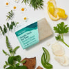 Ursa Major Hoppin' Fresh Bar Soap (5 oz) - product shown with wrapper torn half off surrounded by ingredients