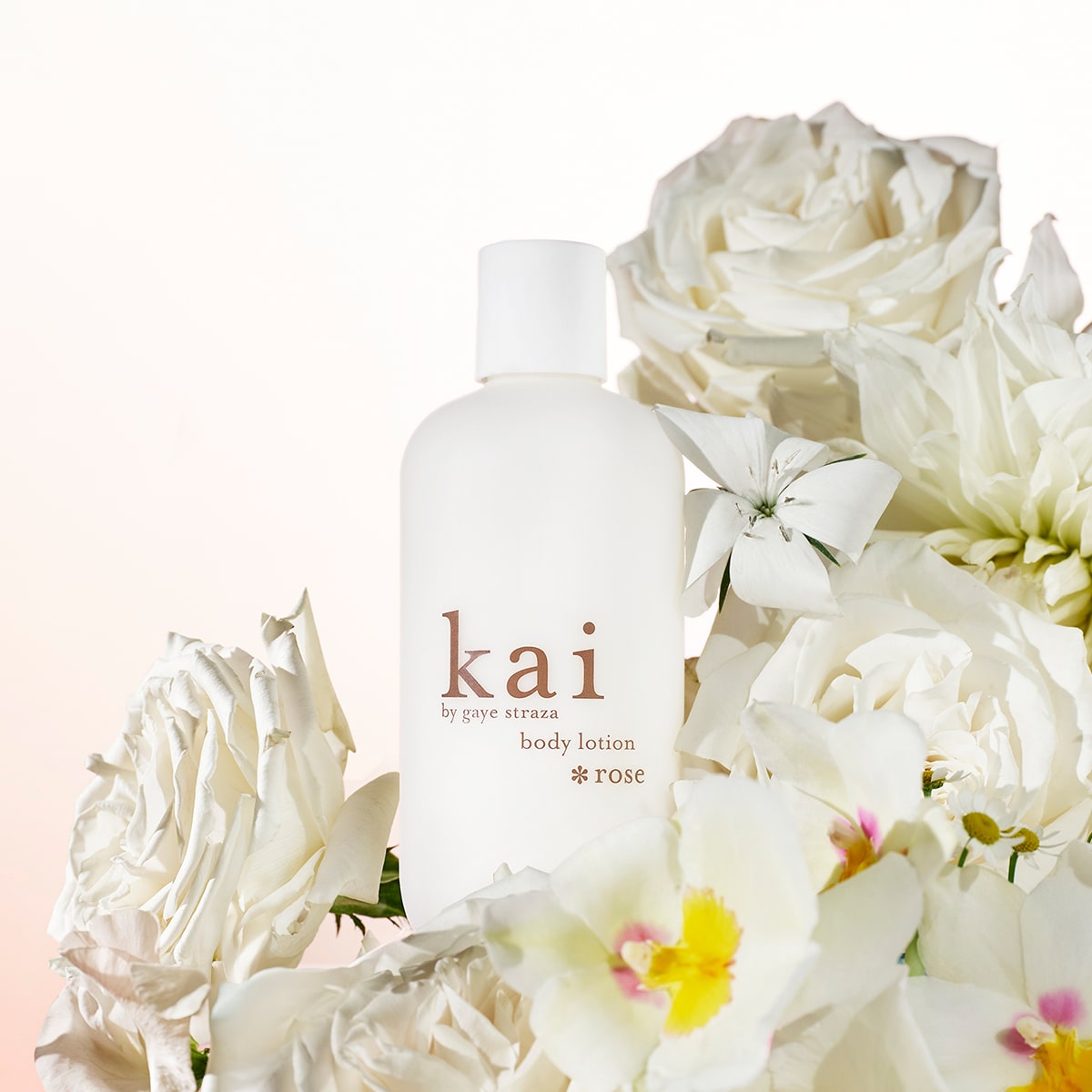 Kai Fragrance Rose Body Lotion (8 oz) bottle surrounded by white flowers on a light pink background