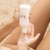 Kai Fragrance Rose Body Lotion (8 oz) being applied on a sandy beach 