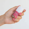 Close up of model wearing Kure Bazaar Nail Lacquer - Sunset (10 ml) and holding bottle