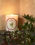 Lifestyle shot of Carriere Freres Siracusa Lemon Candle (185 g) shown lit with florals in the foreground