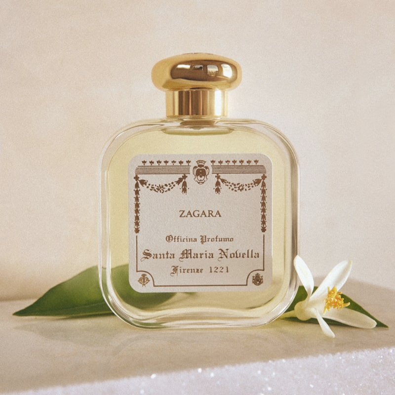 Lifestyle shot of Santa Maria Novella Orange Blossom (Zagara) Cologne - 100 ml with orange blossom flower next to bottle