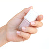 Close up of model wearing Kure Bazaar Nail Lacquer - Rose Snow (10 ml) and holding bottle