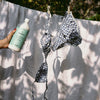 Kerzon Fragranced Laundry Soap - Super Frais (1 L) - product shown being held up in front of curtain with bikini on cloths line. 