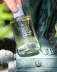 Lifestyle shot/close up of Kerzon Tuileries Palais-Royal Eau de Toilette (100 ml) in a garden with a sculpture of a figure in the background